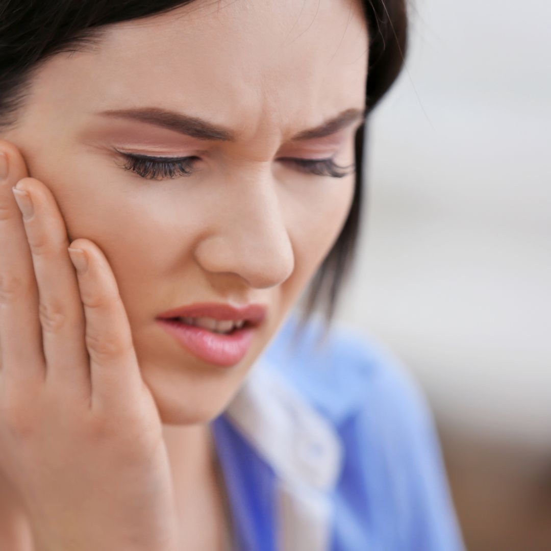 Woman experiencing tooth pain and jaw discomfort, indicating possible dental issue requiring professional care.