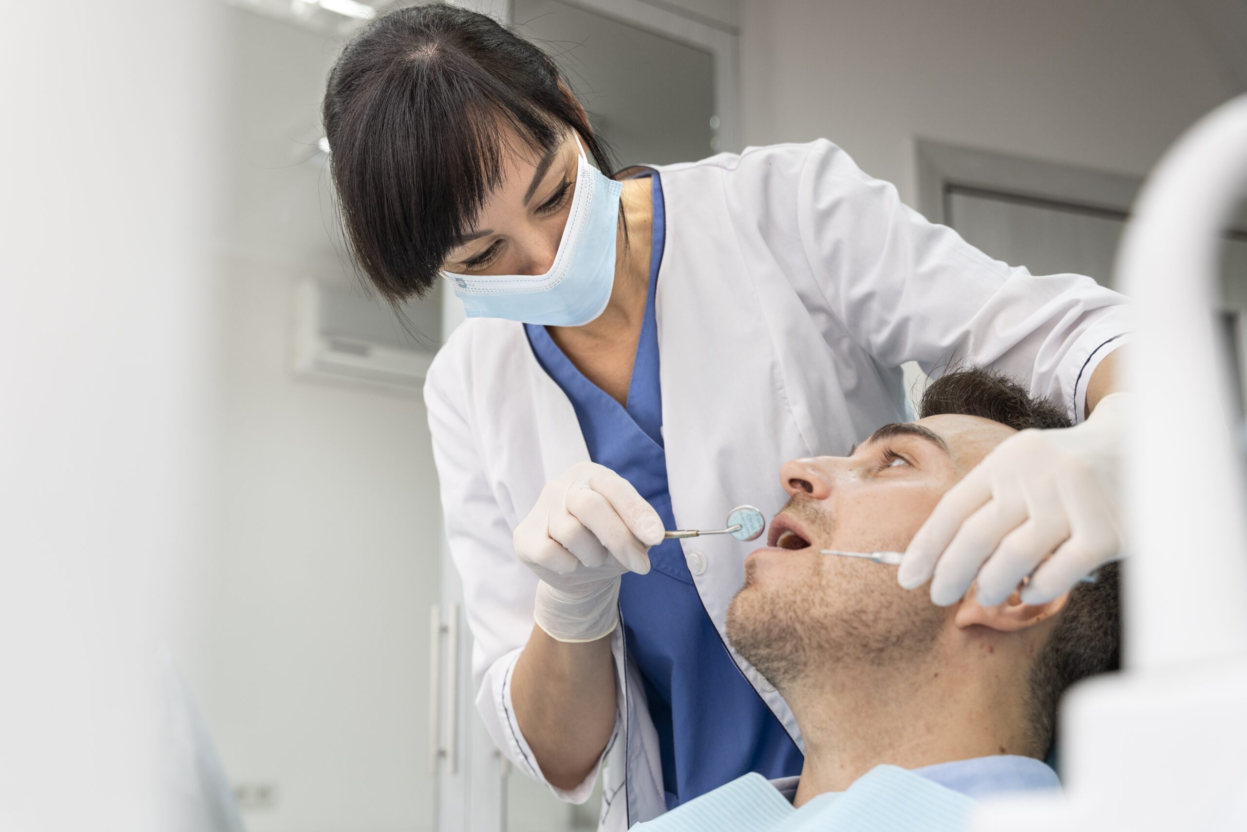 Dentist examining a patient’s teeth with a dental mirror during a routine checkup in the clinic.