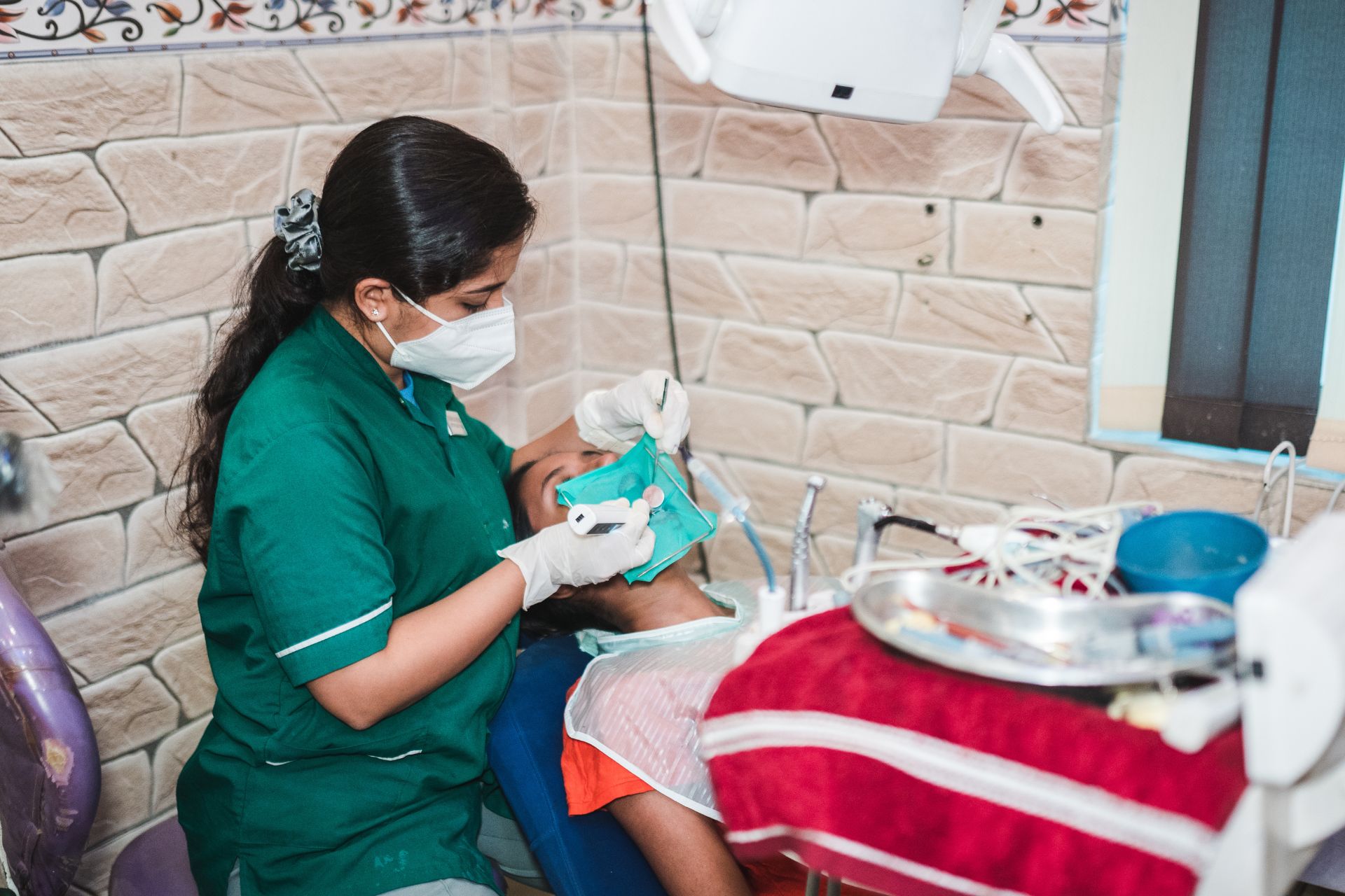 Dentist performing procedure on a patient in a clinic with a textured light brick wall design.